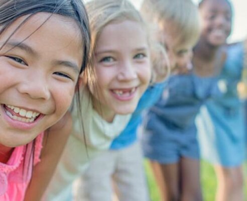 Kids at summer camp arms over shoulders in a circle smiling