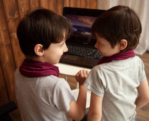 Young brothers learning remotely at home together on a laptop