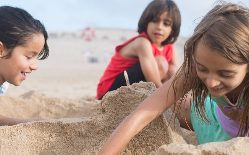 three kids playing at the beach in the sand