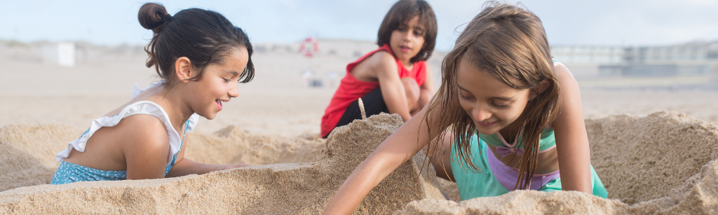 three kids playing at the beach in the sand