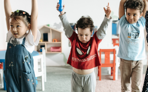 group of kids standing and reaching high