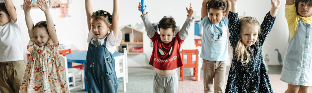 group of kids standing and reaching high