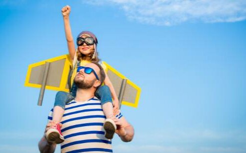 father and child with pay wings and fist pump