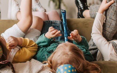 Kids upside down on couch with party noise makers