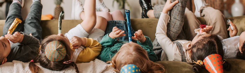 Kids upside down on couch with party noise makers