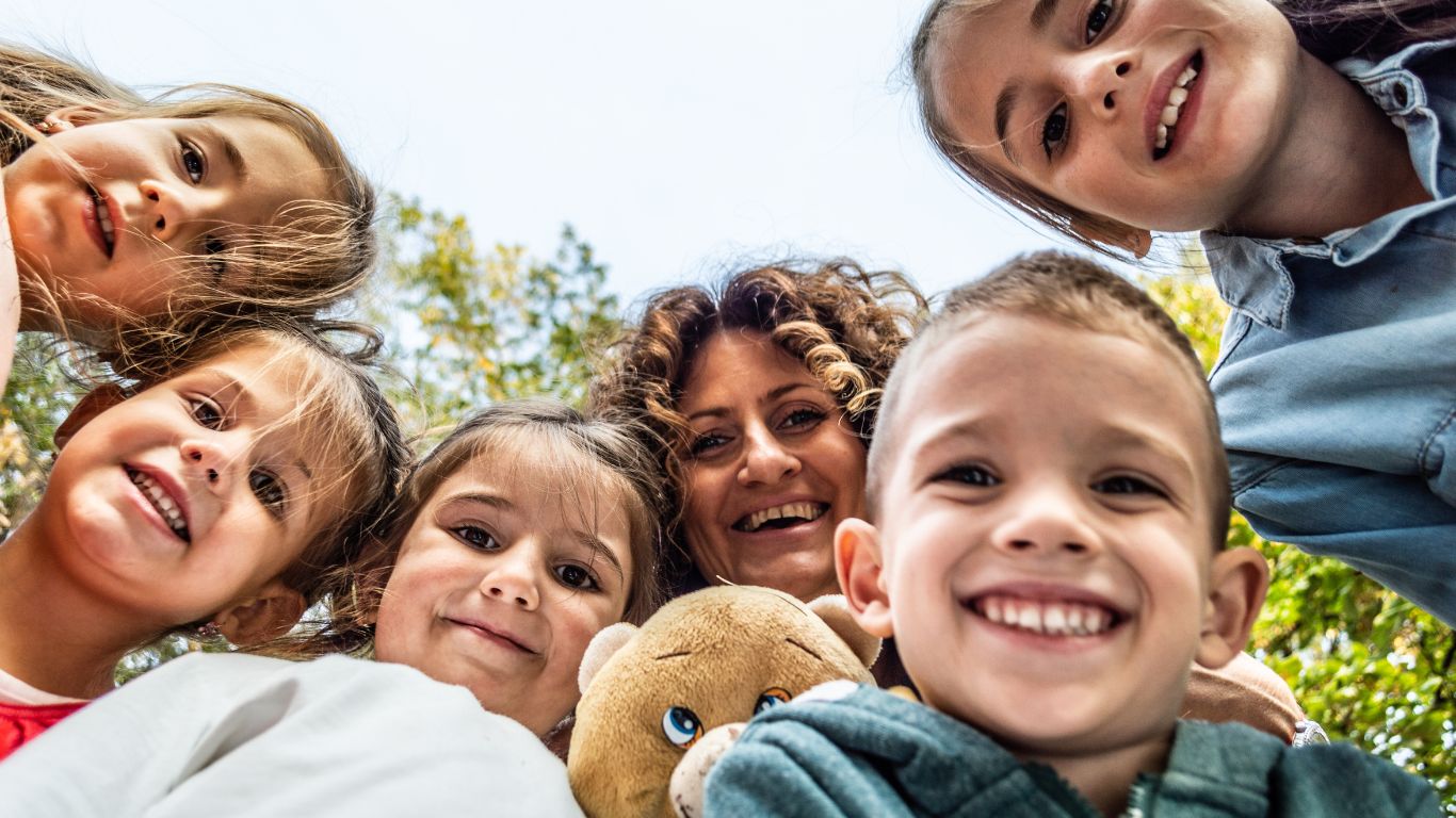 Women and children smiling and looking down at the camera for a pose