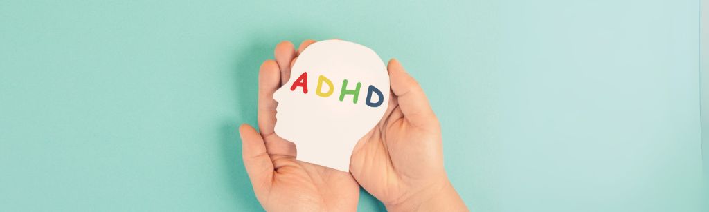 hands holding a cut out head with the letters ADHD
