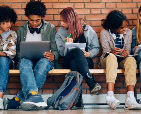 teens sitting on bench in front of brick wall