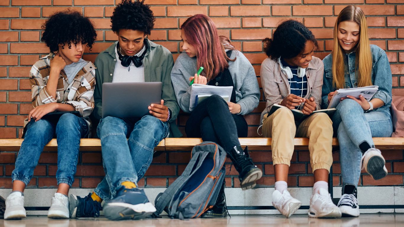 teens sitting on bench in front of brick wall