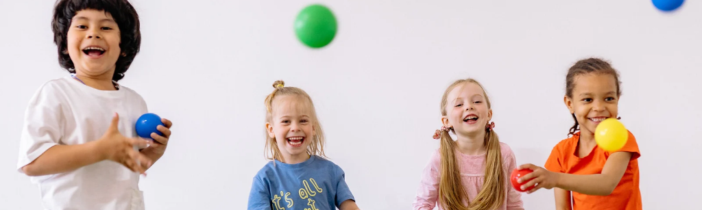 Happy kids playing with colourful balls.