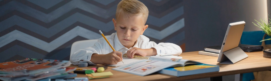 Boy writing on desk with stationery.